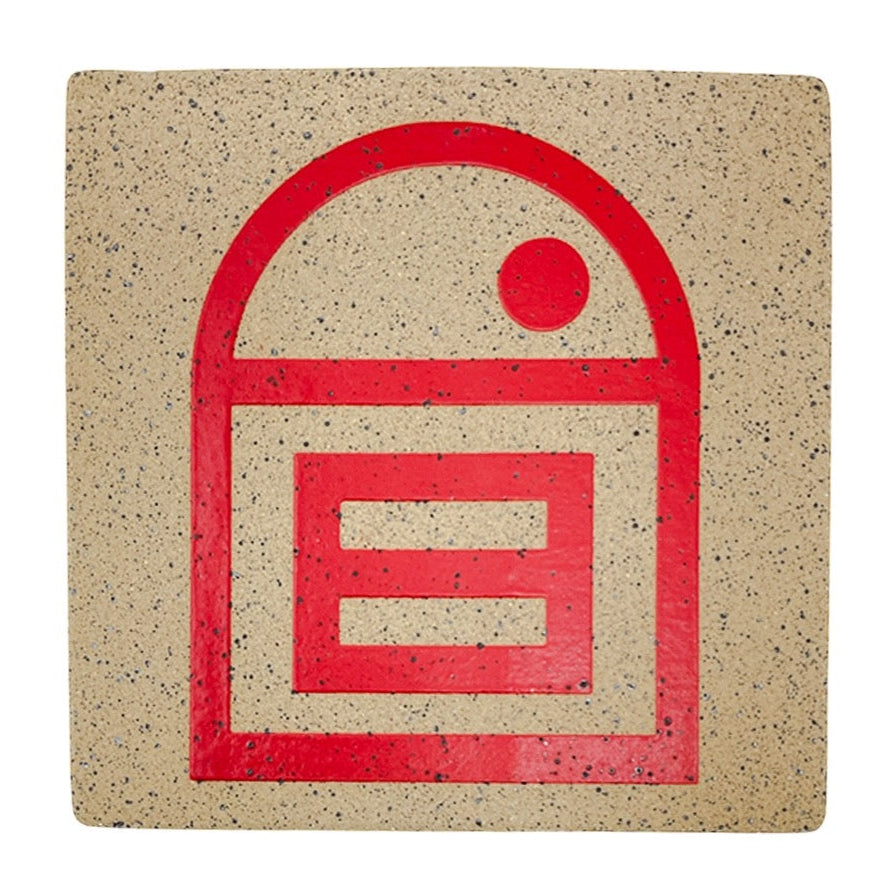 A 4-inch square stoneware tile with a matte red house of equality symbol in the center, on a speckled beige background.